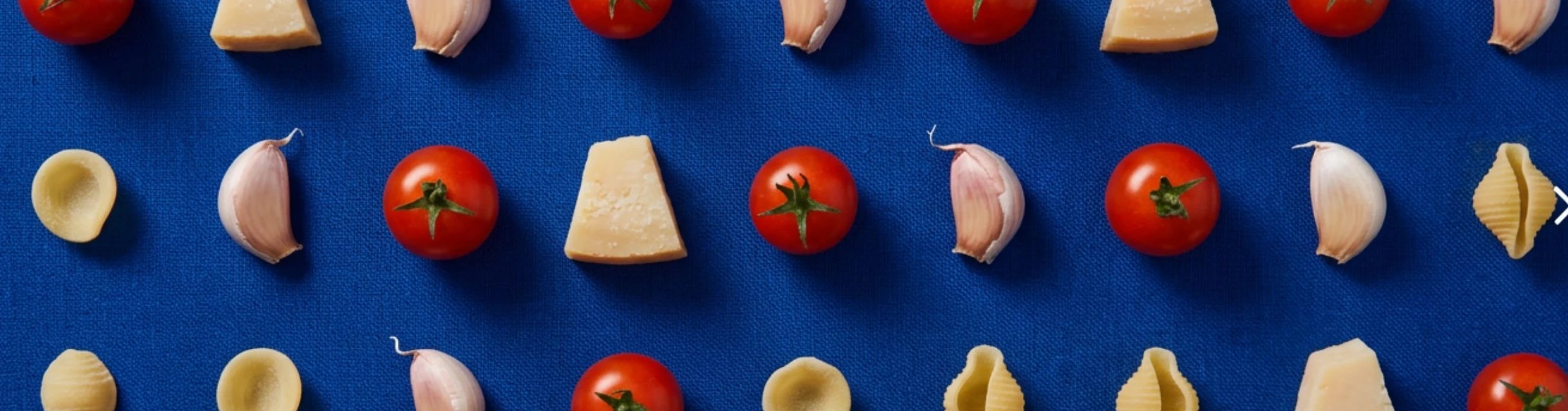 Tomates, ajo y hierbas frescas ordenados en retícula sobre lino azul