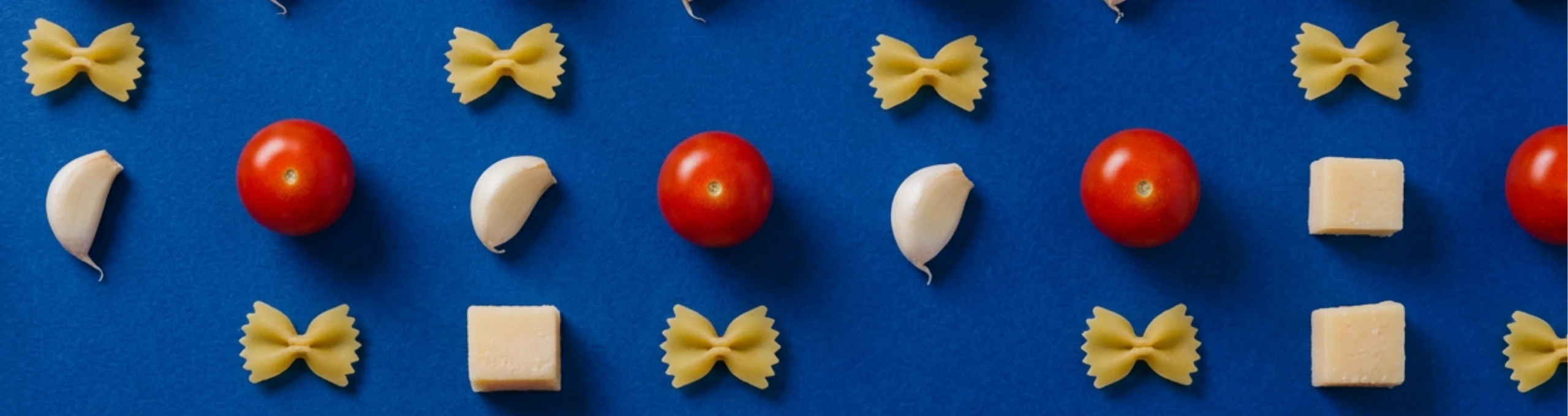Tomates, ajo y albahaca ordenados en retícula sobre lino azul